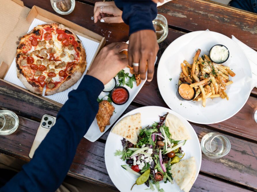 Students sharing pizza, wings, fries, and more at a restaurant near Georgia Tech